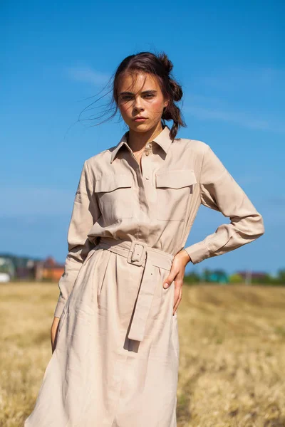 Joven modelo morena hermosa en un vestido beige posando contra — Foto de Stock