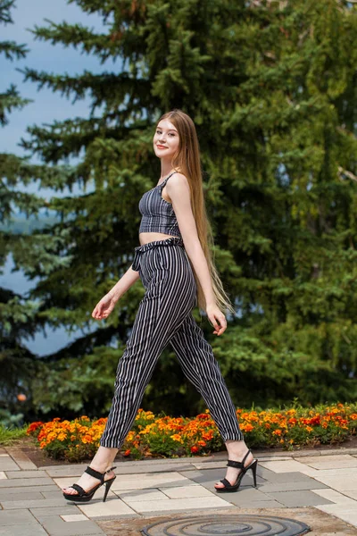 Молодая красивая женщина в полосатых брюках ходит по улице , — стоковое фото