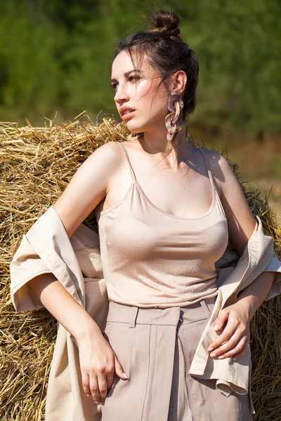 Young beautiful brunette  model in a beige dress posing against — Stock Photo, Image