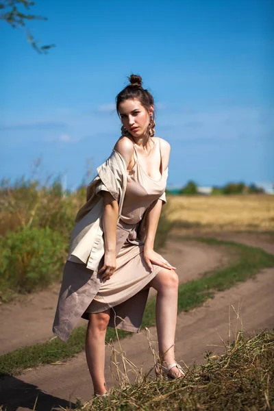 Красивая девушка в бежевом костюме позирует на фоне стога сена — стоковое фото