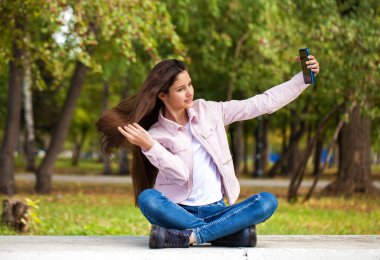 Esmer kız otururken bir cep telefonu kendini fotoğraflar 