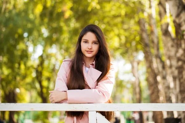 Πορτρέτο ενός νεαρού μελαχρινή κορίτσι σε ροζ παλτό σε ένα φόντο o — Φωτογραφία Αρχείου