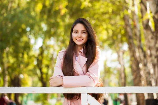 Retrato de una joven morena con abrigo rosa sobre un fondo o — Foto de Stock