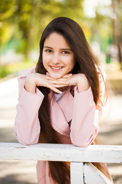 Ritratto di una giovane ragazza bruna in cappotto rosa su sfondo o — Foto Stock