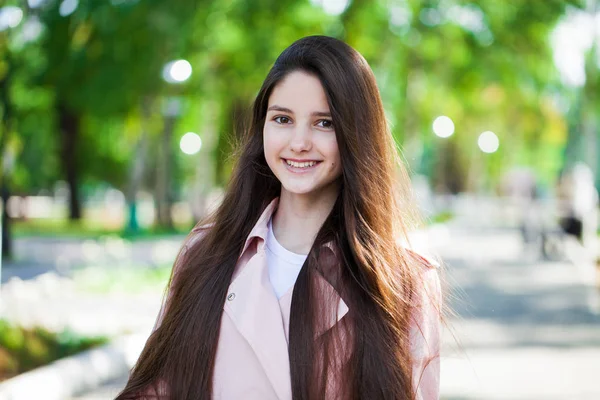 Portrait d'une jeune fille brune en manteau rose sur un fond o — Photo