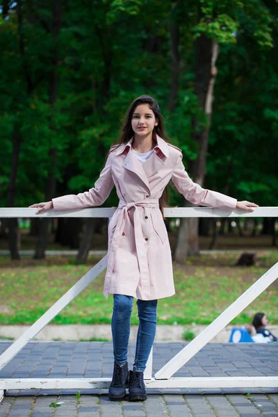 Portrait of a young brunette girl in pink coat on a background o — Stock Photo, Image