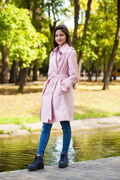 Portrait d'une jeune fille brune en manteau rose sur un fond o — Photo