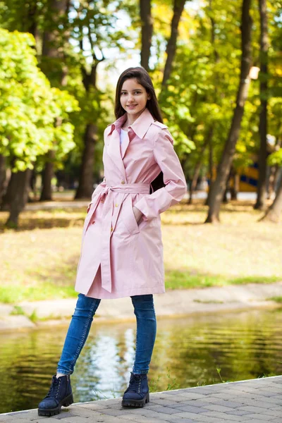 Portret młodej dziewczyny Brunetki w różowym płaszczu na tle o — Zdjęcie stockowe