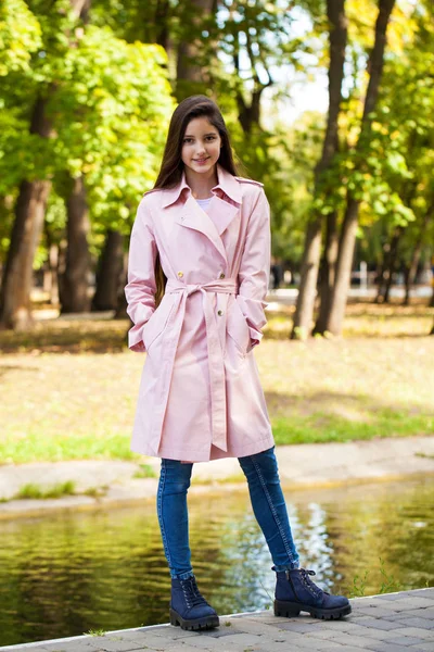 背景にピンクのコートを着た若いブルネットの女の子の肖像画 — ストック写真