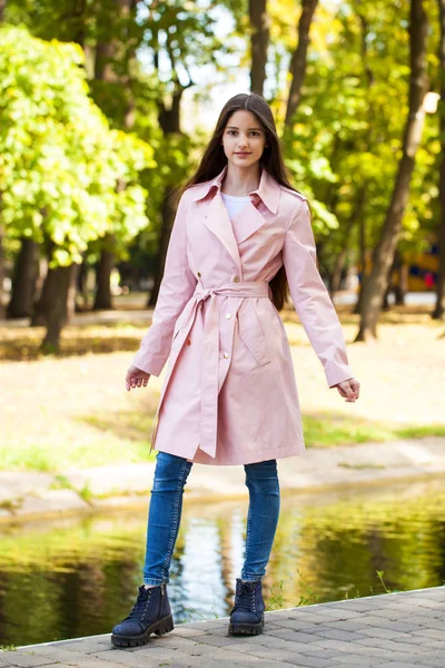 Retrato de uma jovem morena de casaco rosa em um fundo o — Fotografia de Stock