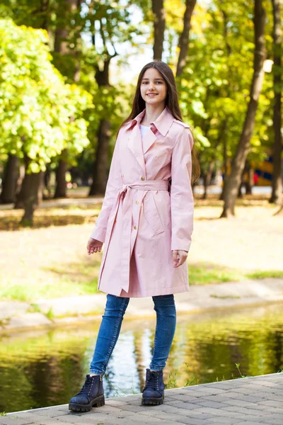 Ritratto di una giovane ragazza bruna in cappotto rosa su sfondo o — Foto Stock