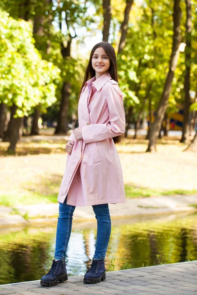 Retrato de una joven morena con abrigo rosa sobre un fondo o — Foto de Stock