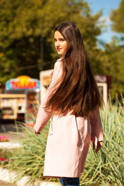 Portret van een jong brunette meisje in roze vacht op een achtergrond o — Stockfoto