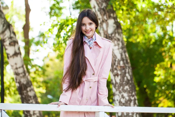 Портрет молодой брюнетки в розовом пальто на заднем плане — стоковое фото