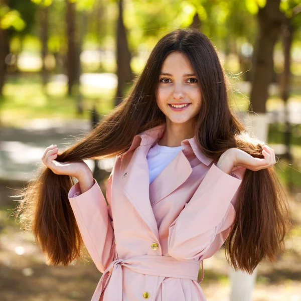 Porträt eines jungen brünetten Mädchens in rosa Mantel auf einem Hintergrund o — Stockfoto