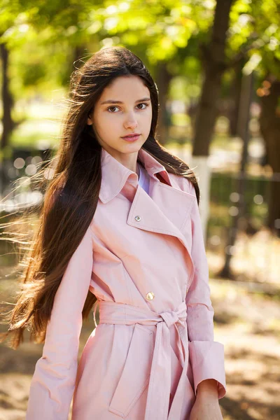 Retrato de una joven morena con abrigo rosa sobre un fondo o —  Fotos de Stock