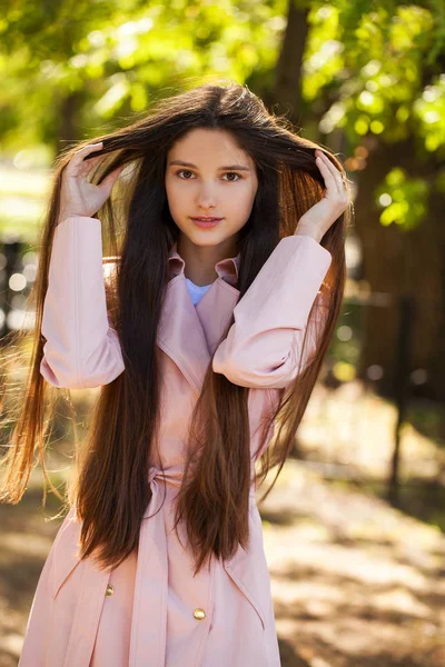 背景上一个年轻的黑发女孩在粉红色外套的肖像 — 图库照片