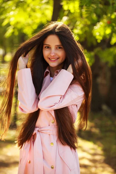 Retrato de una joven morena con abrigo rosa sobre un fondo o — Foto de Stock