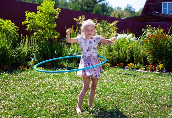 Meisje spelen met hoelahoep in haar tuin — Stockfoto