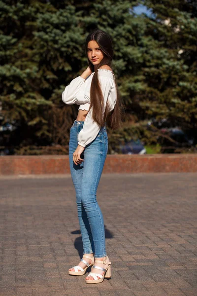 Hezká, elegantní brunetka v modrých džínách a bílé blůze — Stock fotografie