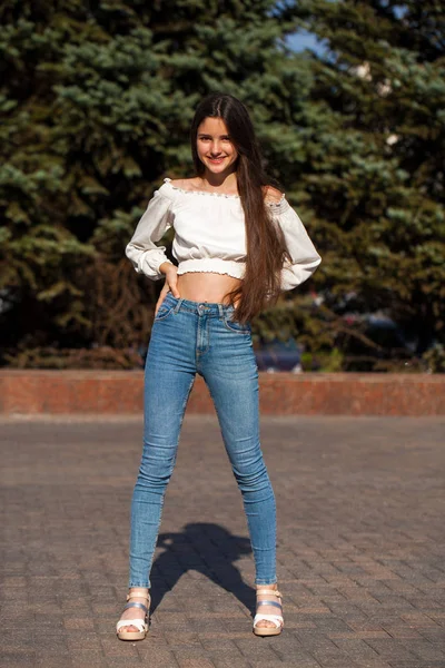 Ganska snygg brunett tjej i blå jeans och vit blus — Stockfoto