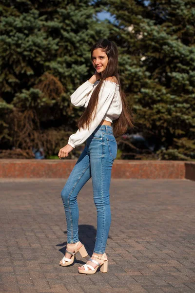 Mooie stijlvolle brunette meisje in blauwe jeans en witte blouse — Stockfoto