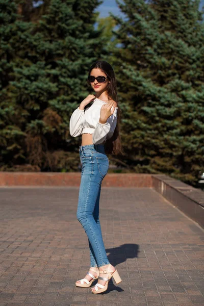 Chica morena bastante elegante en vaqueros azules y blusa blanca —  Fotos de Stock