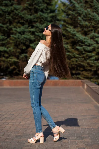 Αρκετά κομψό μελαχρινή κορίτσι με μπλε τζιν και λευκή μπλούζα — Φωτογραφία Αρχείου
