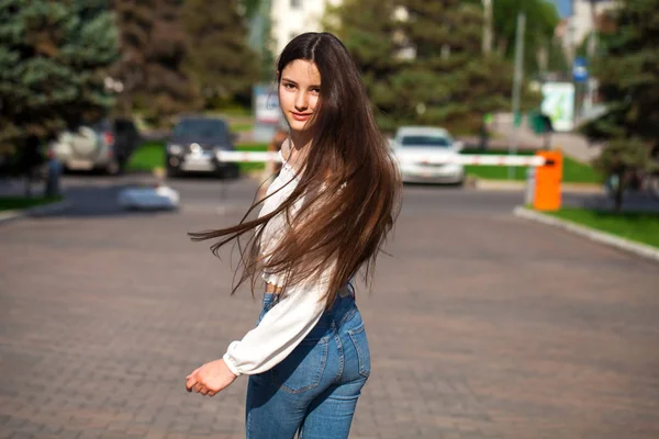 Joven hermosa morena mujer en jeans y blusa blanca caminando —  Fotos de Stock