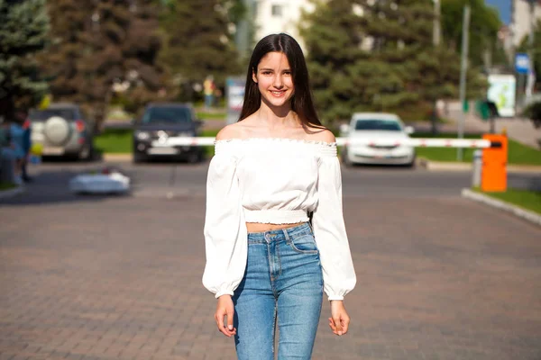 Joven hermosa morena mujer en jeans y blusa blanca caminando —  Fotos de Stock