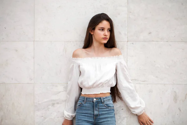 Joven chica hermosa sobre un fondo de una pared de mármol blanco — Foto de Stock