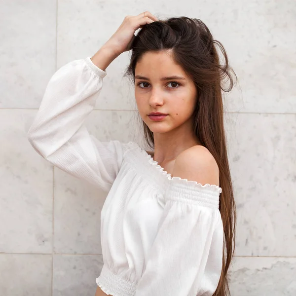 Menina bonita nova em um fundo de uma parede de mármore branco — Fotografia de Stock