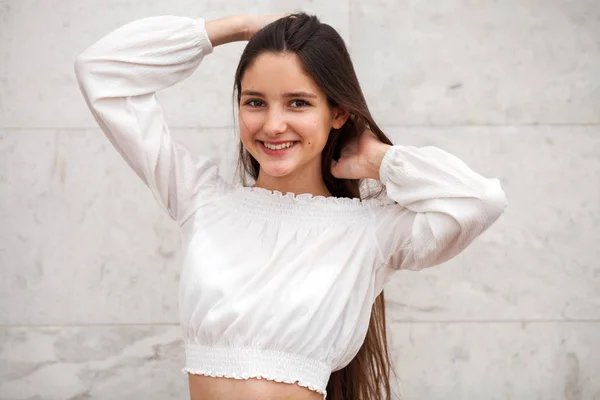 Menina bonita nova em um fundo de uma parede de mármore branco — Fotografia de Stock