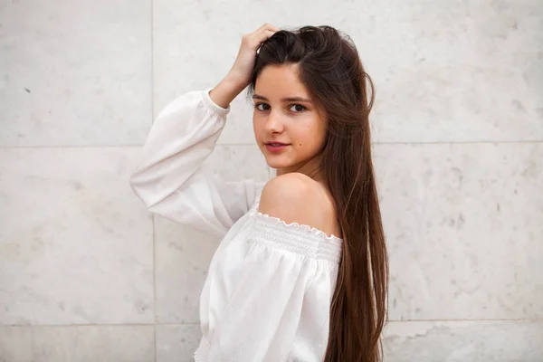 Menina bonita nova em um fundo de uma parede de mármore branco — Fotografia de Stock