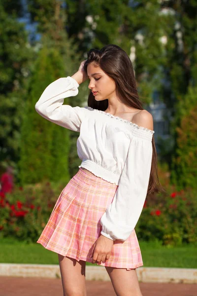 Довольно стильная брюнетка в клетчатой юбке и белой блузке — стоковое фото