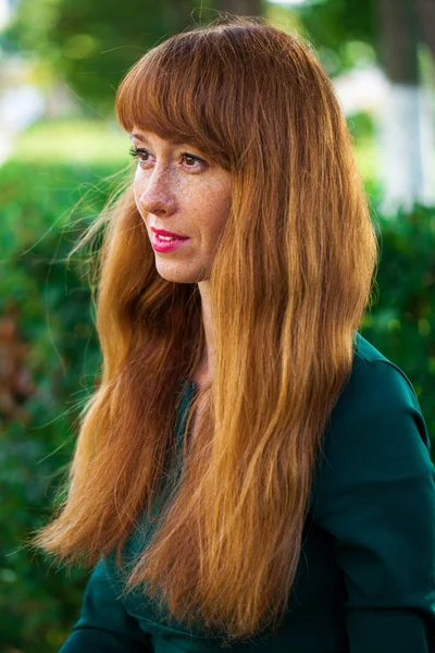 Linda jovem mulher de cabelo vermelho posando no parque de verão — Fotografia de Stock