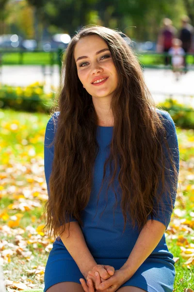 年轻的美丽的黑发女人在秋天公园的蓝色礼服 — 图库照片