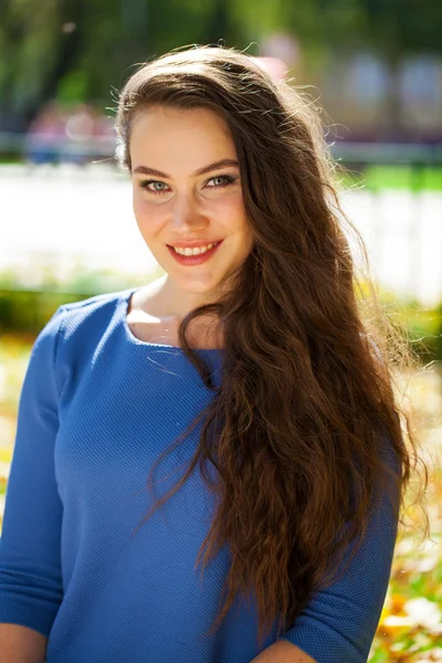 Jonge mooie brunette vrouw in blauwe jurk in herfst Park — Stockfoto