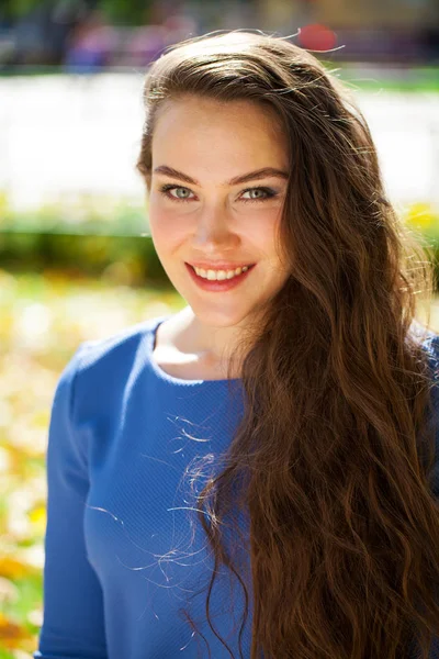 Young beautiful brunette woman in blue dress in autumn park — Stock Photo, Image