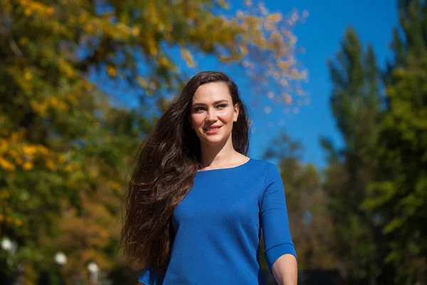 Mooie brunette vrouw in een blauwe jurk wandelen op straat, — Stockfoto