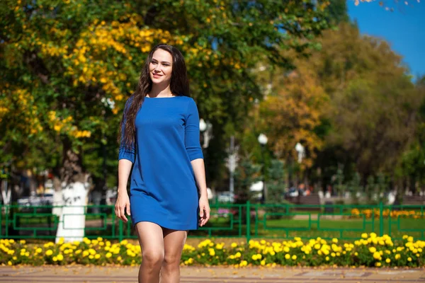 Schöne brünette Frau in einem blauen Kleid zu Fuß auf der Straße, — Stockfoto