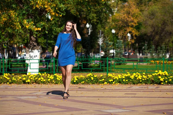 Beautiful brunette woman in a blue dress walking on the street, — Stock Photo, Image