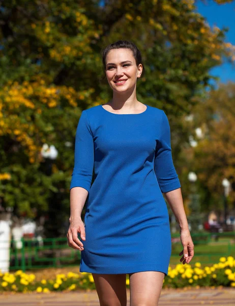Mooie brunette vrouw in een blauwe jurk wandelen op straat, — Stockfoto