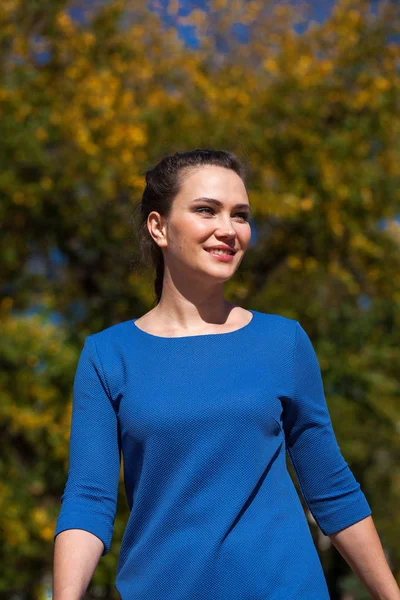 Mooie brunette vrouw in een blauwe jurk wandelen op straat, — Stockfoto