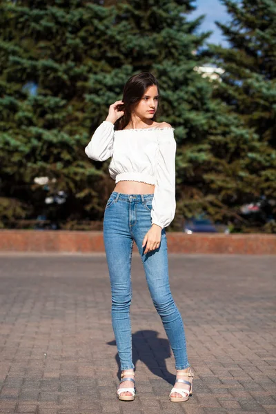 Jolie fille brune élégante en jean bleu et chemisier blanc — Photo