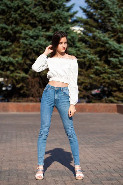 Jolie fille brune élégante en jean bleu et chemisier blanc — Photo