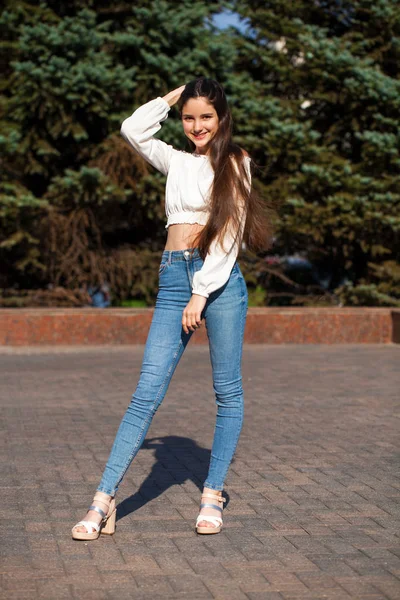 Ziemlich stylisches brünettes Mädchen in blauen Jeans und weißer Bluse — Stockfoto