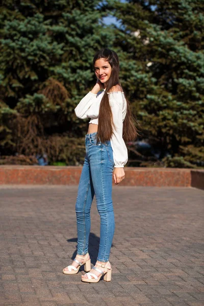 Ganska snygg brunett tjej i blå jeans och vit blus — Stockfoto