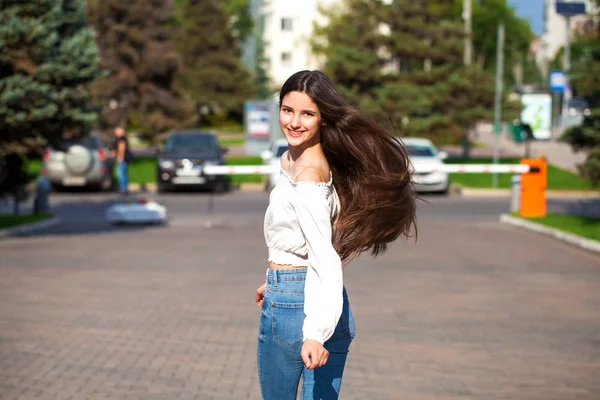 Joven hermosa morena mujer en jeans y blusa blanca caminando —  Fotos de Stock