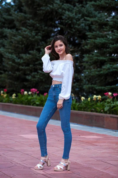 Ziemlich stylisches brünettes Mädchen in blauen Jeans und weißer Bluse — Stockfoto